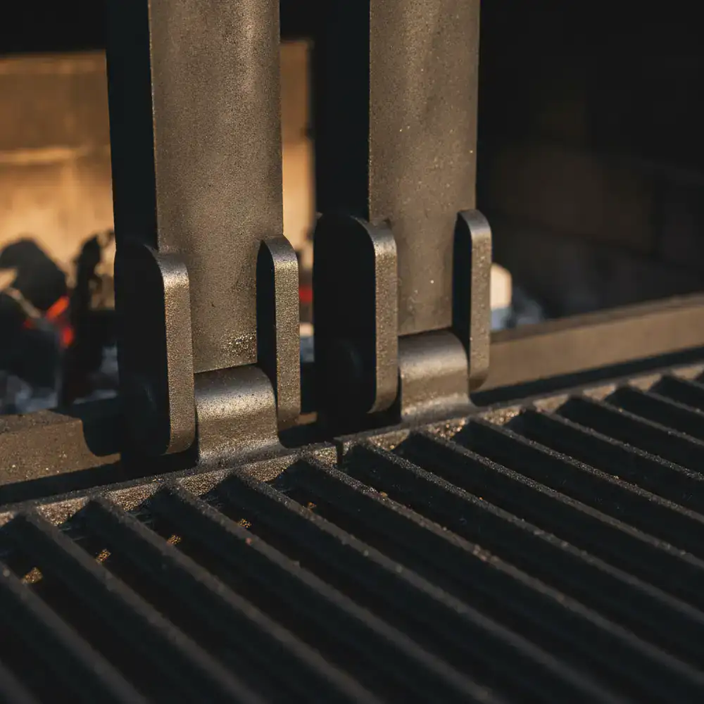 Close up view of the thick steel hinges and heavy cast iron grates on a Golden BBQ grill.