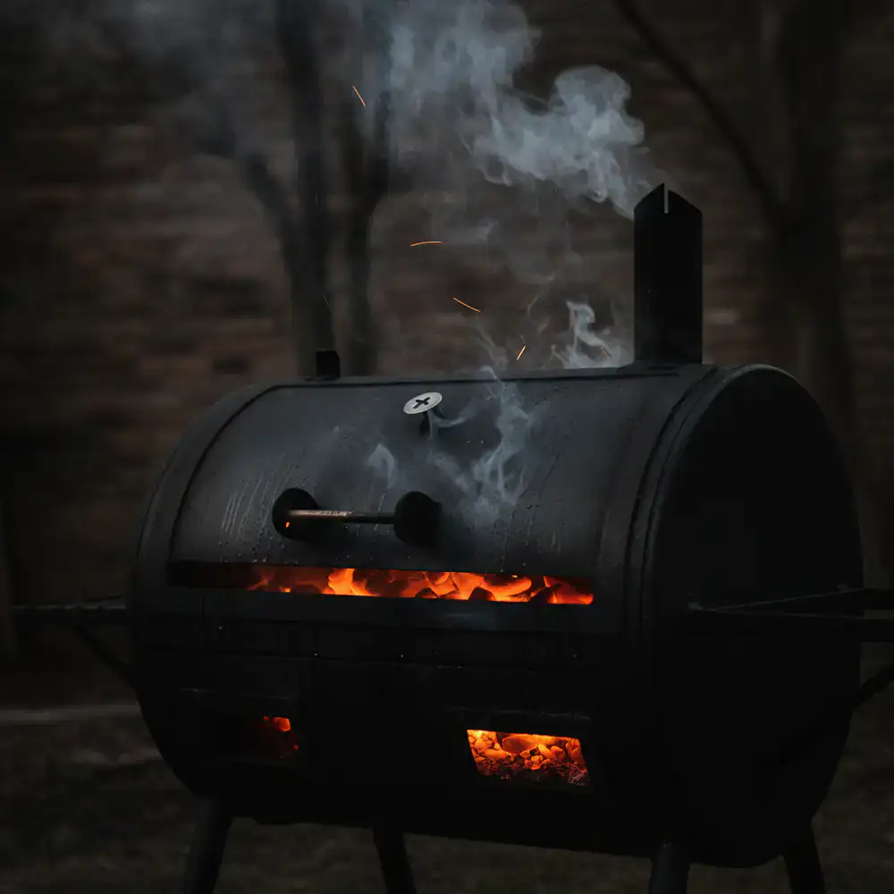 Classic charcoal smoker with glowing embers and smoke